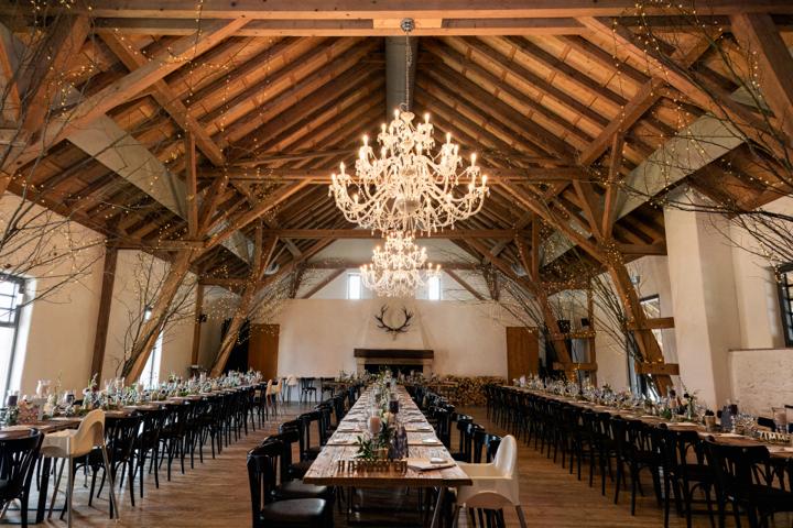 Eleganter Bankettsaal im Hofgut Maisenburg mit großen Holzbalken und einem imposanten Kronleuchter